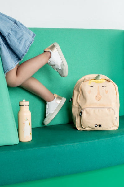 Trixie 500ml stainless steel kids water bottle with Mrs. Unicorn design next to child on green couch and matching unicorn backpack